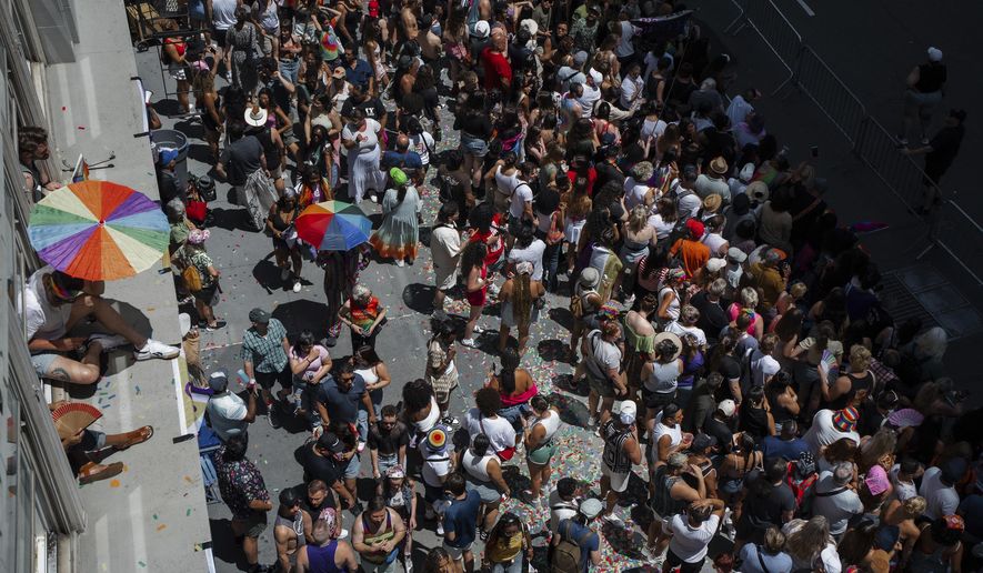 Revelers crowd the sidewalk and peer from windowsills during the Pride March on Sunday, June 29, 2025, in New York. (AP Photo/Olga Fedorova)