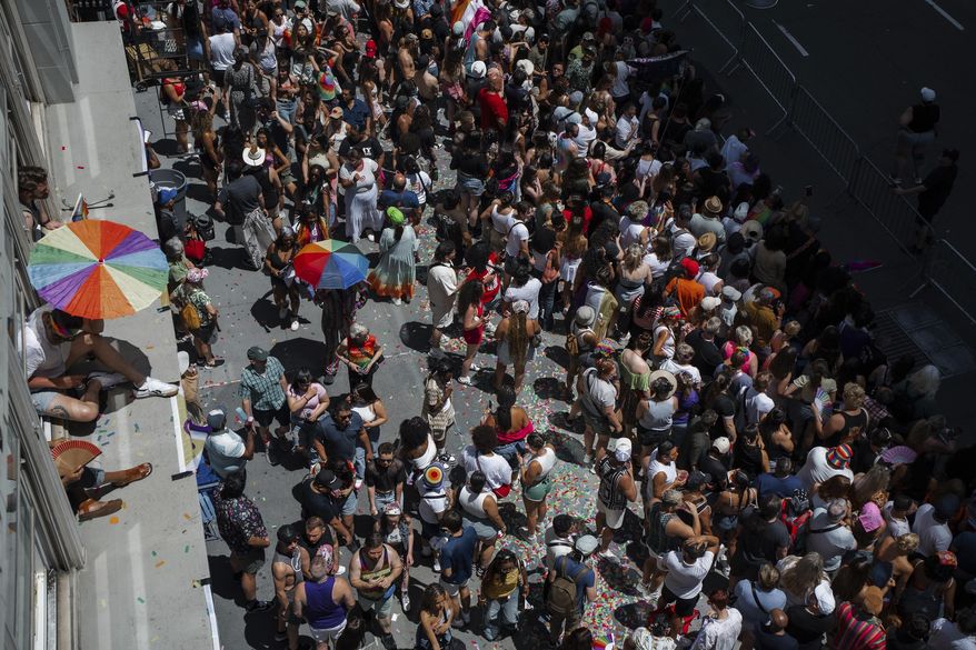 Revelers crowd the sidewalk and peer from windowsills during the Pride March on Sunday, June 29, 2025, in New York. (AP Photo/Olga Fedorova)