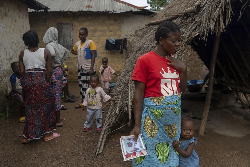 Roseline Phay, 32, stands with her daughter Pauline outside their home in Bong County, Liberia, Saturday, June 14, 2025. (AP Photo/Annie Risemberg)