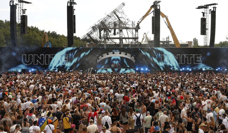 People listen to Odymel B2B and Pegassi performing at the Tomorrowland music festival in Boom, Belgium, Friday, July 18, 2025, two days after a huge fire on Wednesday severely damaged the main stage, rear. (AP Photo/Omar Havana)