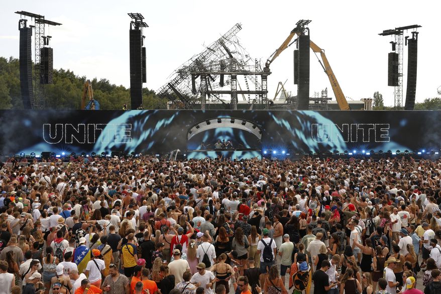 People listen to Odymel B2B and Pegassi performing at the Tomorrowland music festival in Boom, Belgium, Friday, July 18, 2025, two days after a huge fire on Wednesday severely damaged the main stage, rear. (AP Photo/Omar Havana)