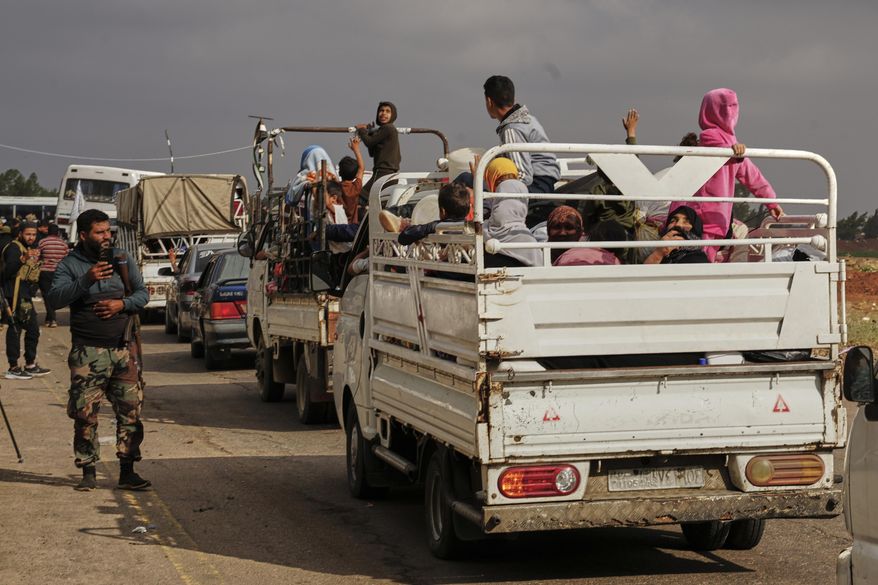 Syrian Bedouin families ride in the back of trucks carrying their belongings, in a convoy led by Red Crescent vehicles in Busra al-Harir, heading to Daraa after being evacuated from Sweida following more than a week of violent clashes, Monday, July 21, 2025. (AP Photo/Malek Khattab)