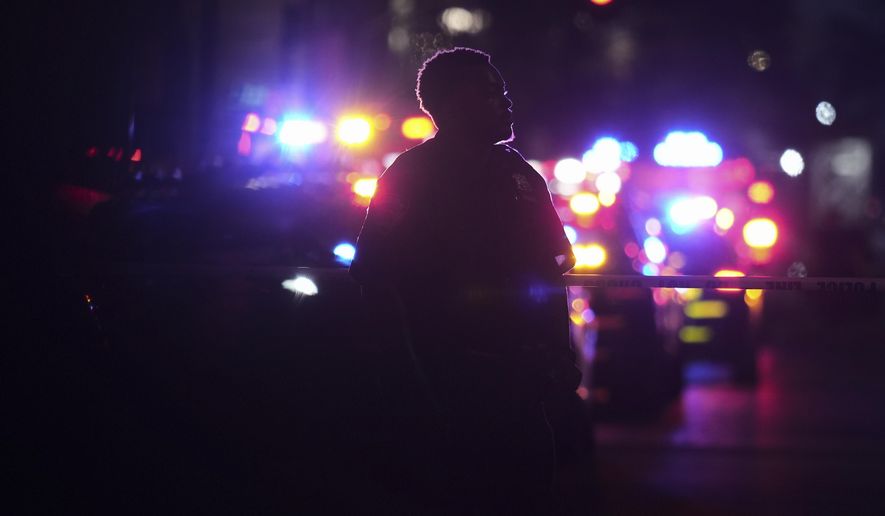 A New York Police officer stands at the scene on 52nd Street outside a Manhattan office building where two people were shot, including a New York police officer, Monday, July 28, 2025, in New York. (AP Photo/Angelina Katsanis)