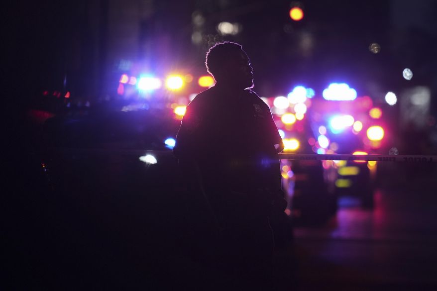 A New York Police officer stands at the scene on 52nd Street outside a Manhattan office building where two people were shot, including a New York police officer, Monday, July 28, 2025, in New York. (AP Photo/Angelina Katsanis)