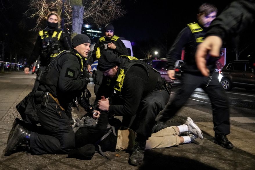 FILE - Police officers detain a man at the Holocaust memorial in Berlin, Germany, after another man was seriously injured, Feb. 21, 2025. (AP Photo/Ebrahim Noroozi, File)