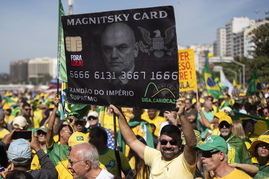 A supporter of former President Jair Bolsonaro holds a photo of Supreme Court Judge Alexandre de Moraes during a demonstration protesting a Supreme Court trial where Bolsonaro faces charges for alleged involvement in a 2022 coup attempt, at Copacabana Beach in Rio de Janeiro, Sunday, Aug. 3, 2025. (AP Photo/Bruna Prado)