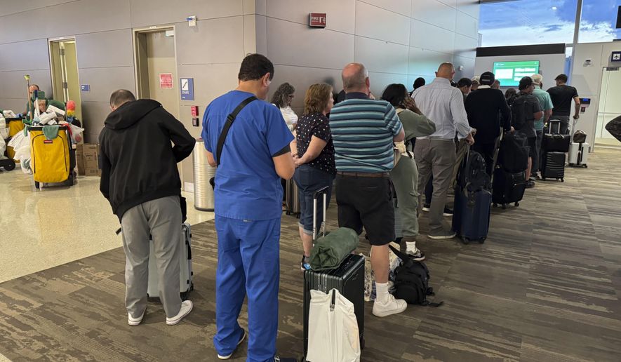 Passengers seeks updates on their delayed flight at Louis Armstrong New Orleans International Airport, Wednesday, Aug. 6, 2025, in Kenner, La. (AP Photo/Jack Brooks) ** FILE **