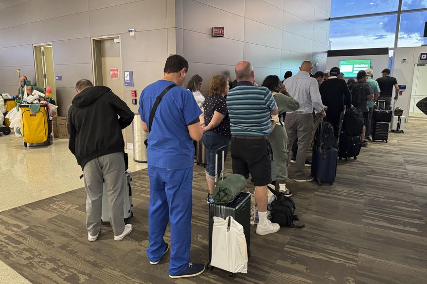 Passengers seeks updates on their delayed flight at Louis Armstrong New Orleans International Airport, Wednesday, Aug. 6, 2025, in Kenner, La. (AP Photo/Jack Brooks) ** FILE **