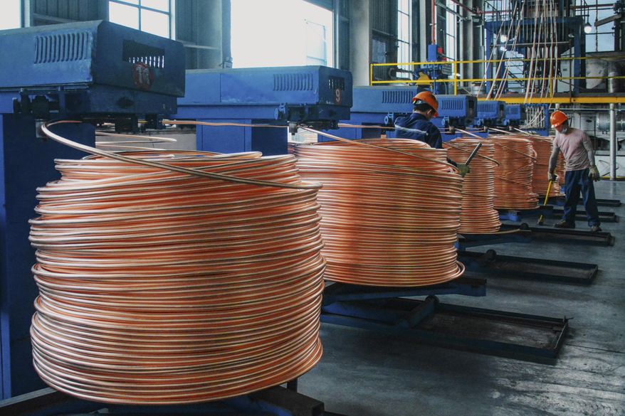 Workers labor as the machines roll up copper rods at a metal melting facility in Yuexi County, central China's Anhui Province on July 11, 2025. (Chinatopix via AP)