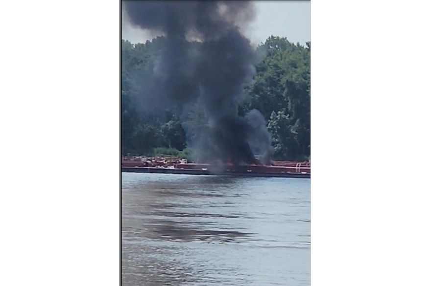 This image provided by Adam Briggs shows smoke fills the air from a barge after a helicopter crash in the Mississippi River near Alton, Ill., on Thursday, Aug. 7, 2025. (Adam Briggs via AP)