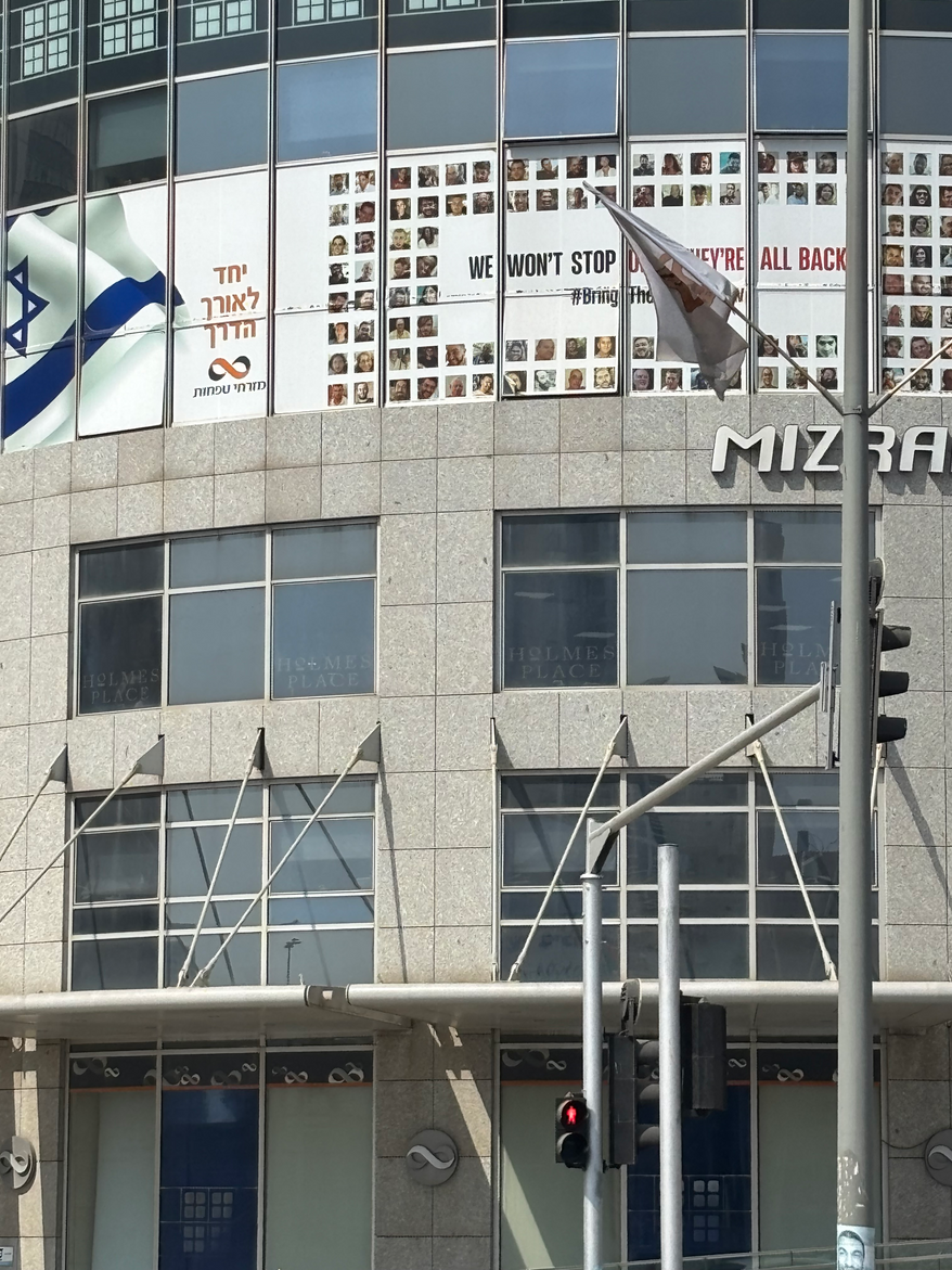 TEL AVIV — Vows to bring home all the hostages abducted by Hamas terrorists on October 7, 2023, are posted everywhere in Tel Aviv. This one is on a building in the area of Menachem Begin Road, where missiles from Iran struck in June of 2025. August 9, 2025. Photo Credit: Cheryl Chumley / The Washington Times