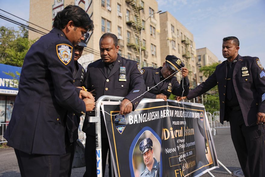 New York Police officers hang a banner for the funeral of officer Didarul Islam, Thursday, July 31, 2025, in New York. (AP Photo/Angelina Katsanis)