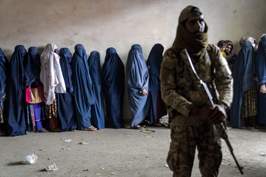 A Taliban fighter stands guard as women wait to receive food rations distributed by a humanitarian aid group, in Kabul, Afghanistan, Tuesday, May 23, 2023. (AP Photo/Ebrahim Noroozi) **FILE**