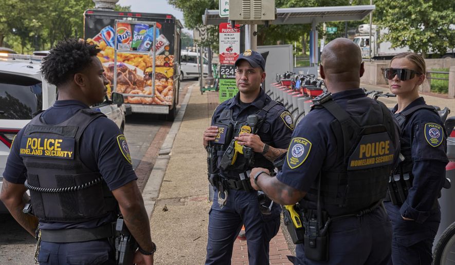 Homeland Security Federal Protective Services agents wait on a tow truck to take away a food truck on the National Mall, Friday, Aug. 15, 2025, in Washington. The owner says his employees were asked for immigration status by ICE and then he was told that the truck's tires were bad and it would have to be towed, though he insists it recently passed DC inspection. (AP Photo/Jacquelyn Martin)