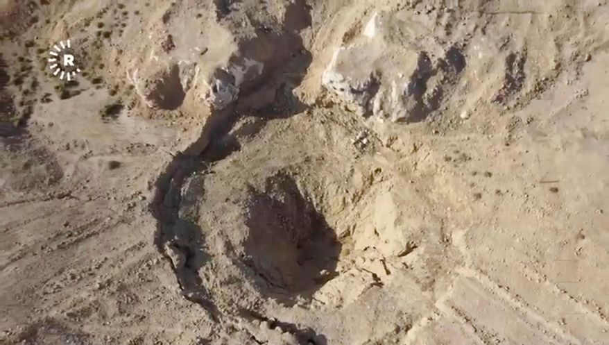 In this image taken from video provided by Rudaw TV, an aerial view shows a sinkhole at the Khasfa site near the northern Iraqi city of Mosul, where authorities have begun excavating a mass grave believed to contain thousands of victims of the Islamic State (IS). Mosul, Iraq, Sunday, Aug. 17, 2025. (Rudaw TV via AP) ** FILE **
