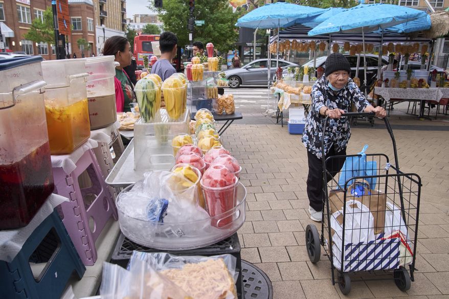 A woman walks past fruit vendors without buying anything, Tuesday, Aug. 19, 2025, as vendors wait for customers in the Columbia Heights neighborhood of northwest Washington. (AP Photo/Jacquelyn Martin)