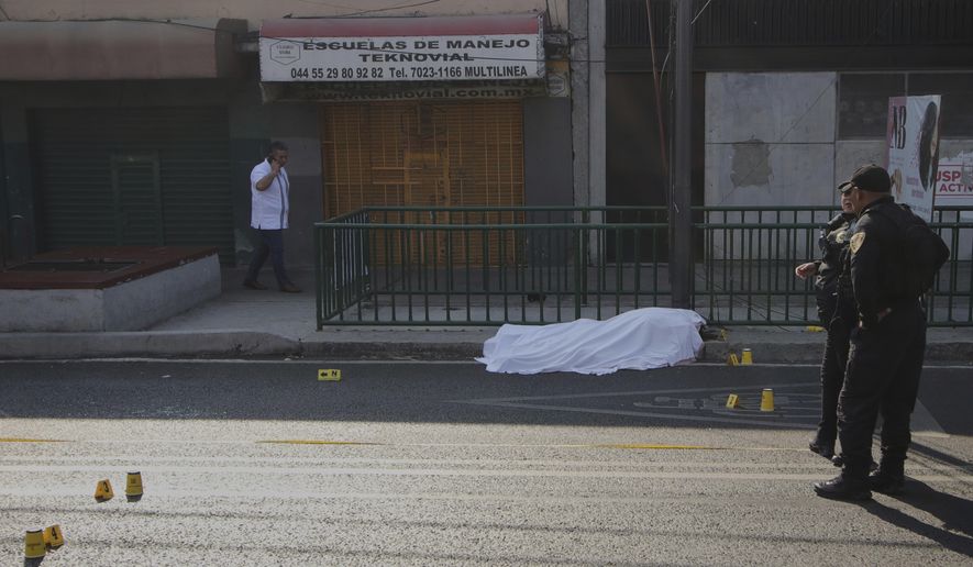 FILE - A body lies covered as police work at the site where the personal secretary and an advisor to Mexico City's mayor were killed by gunmen on a motorcycle, in Mexico City, May 20, 2025. (AP Photo/Tristan Velazquez, File)