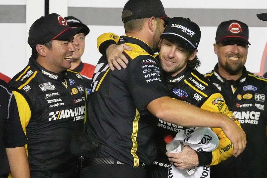 Ryan Blaney, second from right, hugs crew members as he celebrates in Victory Lane after winning the NASCAR Cup Series auto race at Daytona International Speedway, Saturday, Aug. 23, 2025, in Daytona Beach, Fla. (AP Photo/John Raoux)
