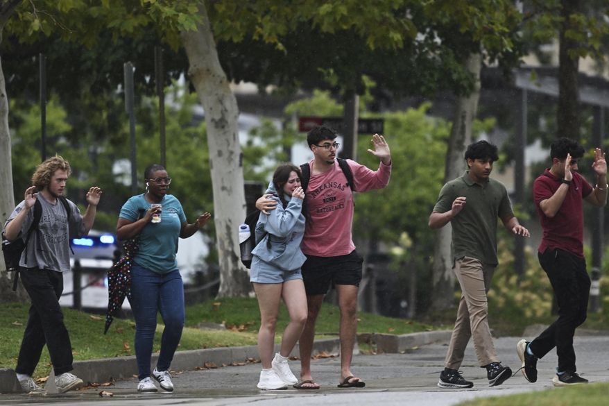 University of Arkansas students and employees evacuate and take shelter Monday, Aug. 25, 2025, in Fayetteville, Ark., as police respond to reports of a shooting. (AP Photo/Michael Woods)