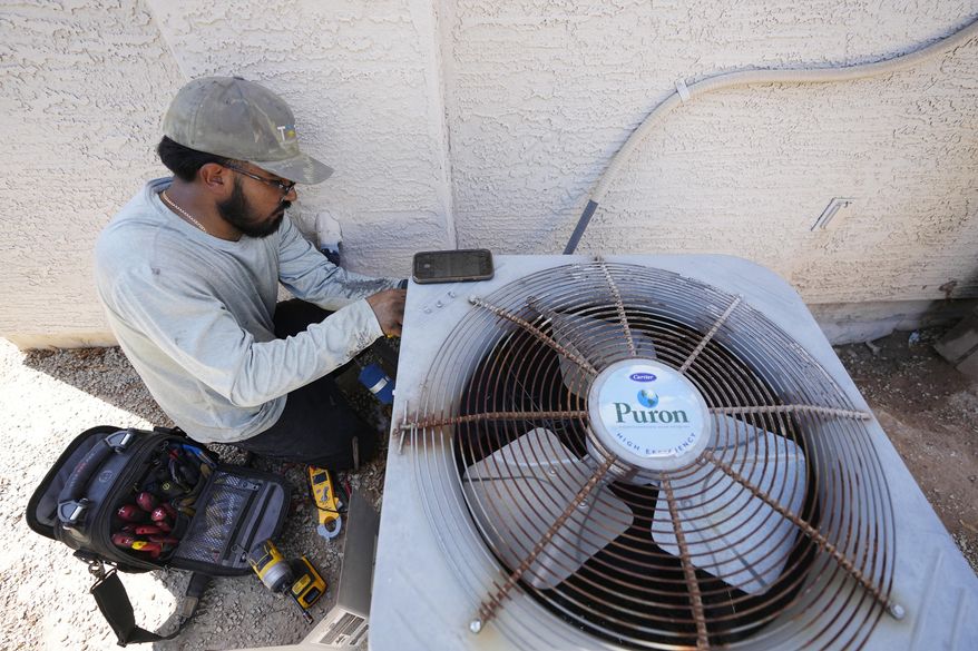 FILE - Total Refrigeration service tech Michael Villa works on replacing a fan motor on an air conditioning unit on July 19, 2023, in Phoenix. (AP Photo/Ross D. Franklin, File)