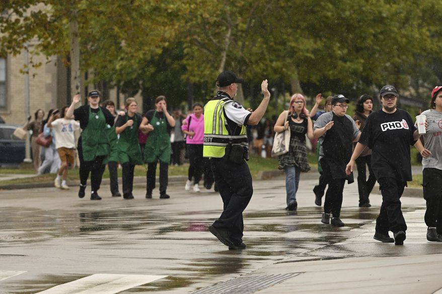 University of Arkansas students and employees evacuate and take shelter Monday, Aug. 25, 2025, in Fayetteville, Ark., as police respond to reports of a shooting. (AP Photo/Michael Woods)