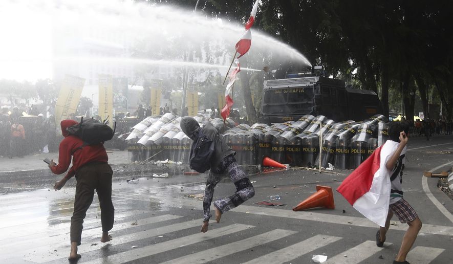People throw rocks at the police during a protest following the death of a delivery rider in clashes between riot police and students protesting against lawmakers' allowances, in Medan, North Sumatra, Indonesia, Friday, Aug. 29, 2025. (AP Photo/Binsar Bakkara)