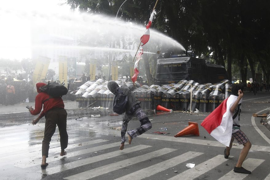 People throw rocks at the police during a protest following the death of a delivery rider in clashes between riot police and students protesting against lawmakers' allowances, in Medan, North Sumatra, Indonesia, Friday, Aug. 29, 2025. (AP Photo/Binsar Bakkara)