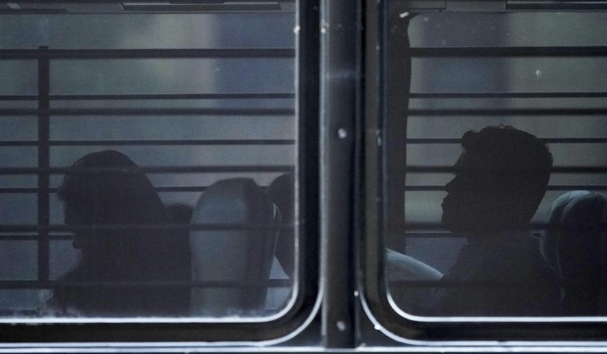 A family from Colombia sits on a bus with tinted and barred windows after they were detained by federal agents following an appearance at immigration court Monday, July 14, 2025, in San Antonio. (AP Photo/Eric Gay) **FILE**
