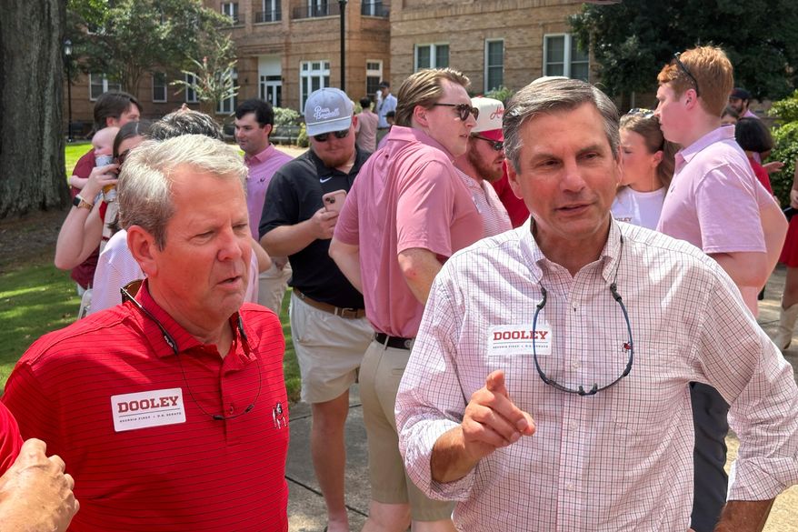 Georgia Gov. Brian Kemp, left, and Republican U.S. Senate candidate Derek Dooley speak to attendees at a tailgate at the University of Georgia in Athens, Ga., on Saturday, Aug. 30, 2025. (AP Photo/Jeff Amy)