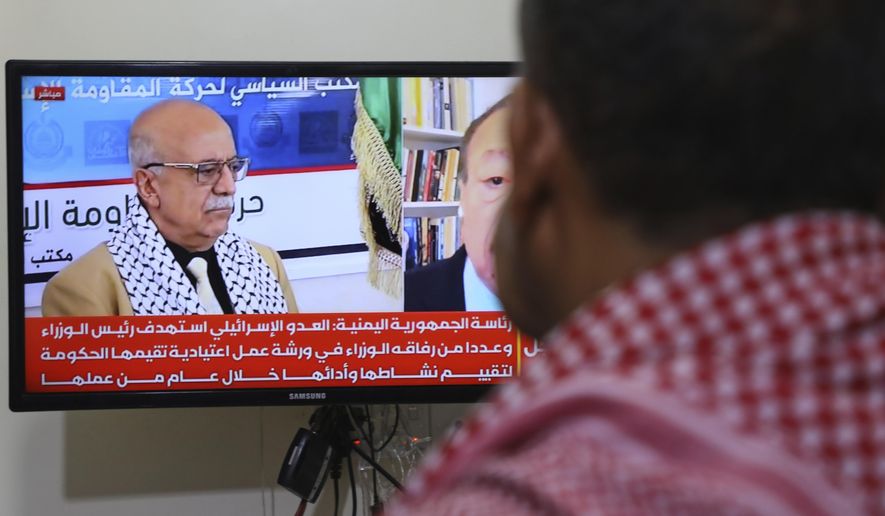 A man watches the news on TV, displaying footage of Ahmed al-Rahawi, the prime minister of the Houthi-controlled government, who was killed, along with others, in Thursday's Israeli strikes on the capital, in Sanaa, Yemen, Saturday, Aug. 30, 2025. (AP Photo/Osamah Abdulrahman)