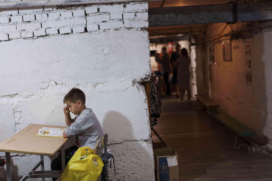 A school boy listens to a teacher during a lesson, in the basement of a municipal building during the first day in school in Bobryk, Sumy region, Ukraine, Monday, Sept. 1, 2025. The Bobryk school was forced to move to the basement due to endless alarms. (AP Photo/Evgeniy Maloletka)