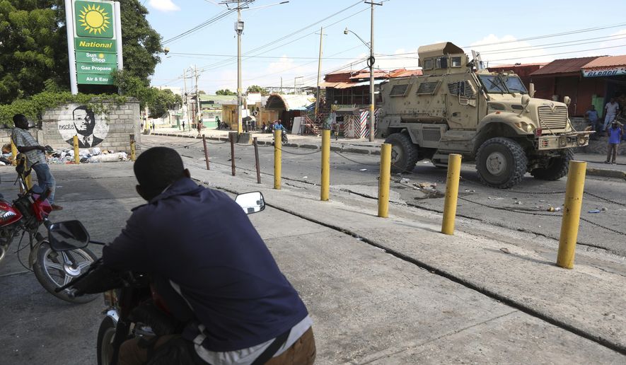 Residents watch a Kenyan police armored vehicle patrolling in Port-au-Prince, Haiti, Tuesday, Sept. 2, 2025. (AP Photo/Odelyn Joseph)