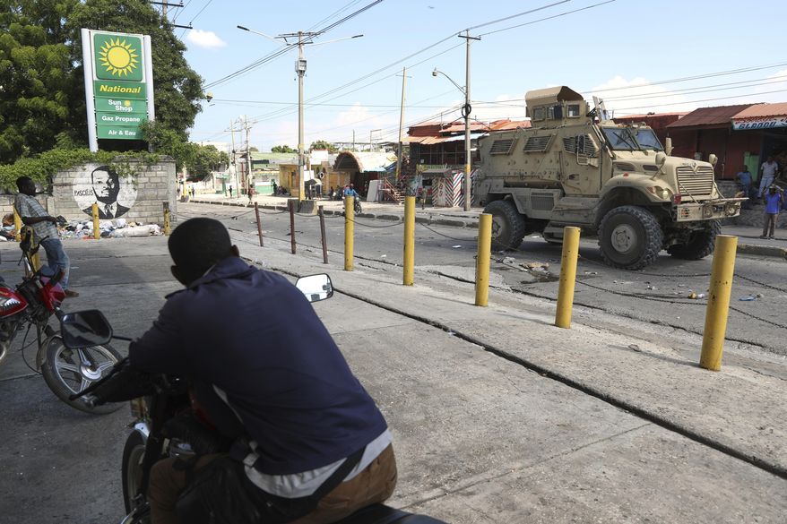 Residents watch a Kenyan police armored vehicle patrolling in Port-au-Prince, Haiti, Tuesday, Sept. 2, 2025. (AP Photo/Odelyn Joseph)