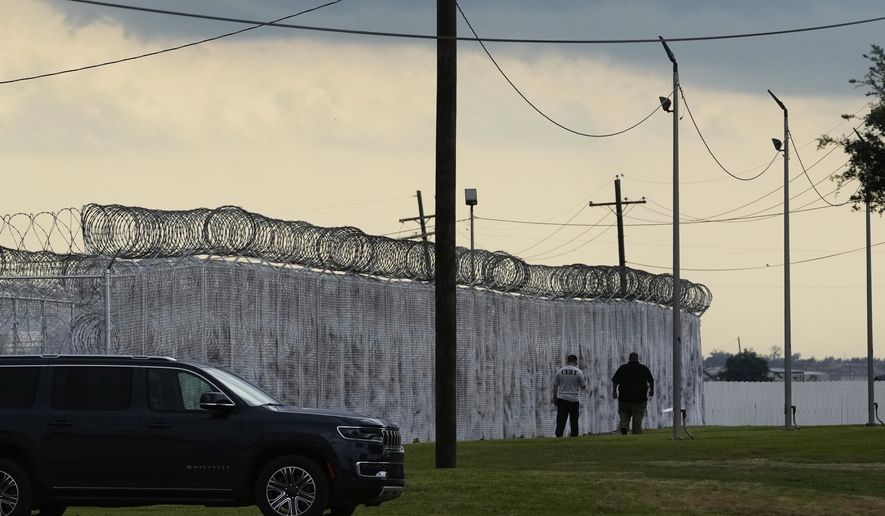 Security walk outside "Camp 57," a facility to house immigration detainees at the Louisiana State Penitentiary in Angola, La., prior to Homeland Security Secretary Kristi Noem touring the facility with Louisiana Gov. Jeff Landry, Attorney General Pam Bondi, and ICE Deputy Director Madison Sheahan, Wednesday, Sept. 3, 2025. (AP Photo/Gerald Herbert)