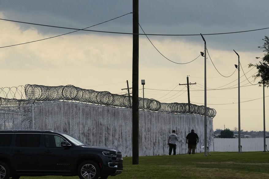 Security walk outside "Camp 57," a facility to house immigration detainees at the Louisiana State Penitentiary in Angola, La., prior to Homeland Security Secretary Kristi Noem touring the facility with Louisiana Gov. Jeff Landry, Attorney General Pam Bondi, and ICE Deputy Director Madison Sheahan, Wednesday, Sept. 3, 2025. (AP Photo/Gerald Herbert)