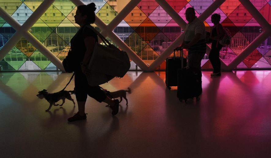 Travelers walk toward an exit at Miami International Airport at the start of the Labor Day weekend, Friday, Aug. 29, 2025, in Miami. (AP Photo/Rebecca Blackwell)