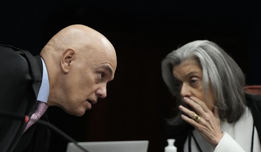 Supreme Court Justices Alexandre de Moraes, left, and Carmen Lucia speak during the verdict and sentencing phase of a trial for those charged in an alleged coup plot to keep former President Jair Bolsonaro in office after his 2022 election defeat, in Brasilia, Brazil, Tuesday, Sept. 9, 2025. (AP Photo/Eraldo Peres)