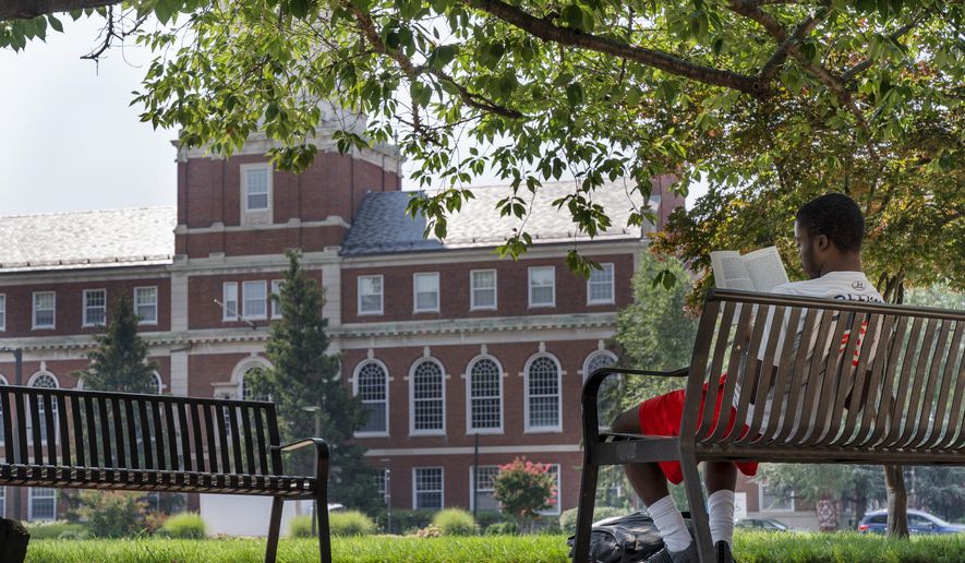 FILE - With the Founders Library in the background, a young man reads on Howard University campus July 6, 2021, in Washington. (AP Photo/Jacquelyn Martin, File)