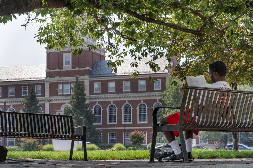 FILE - With the Founders Library in the background, a young man reads on Howard University campus July 6, 2021, in Washington. (AP Photo/Jacquelyn Martin, File)
