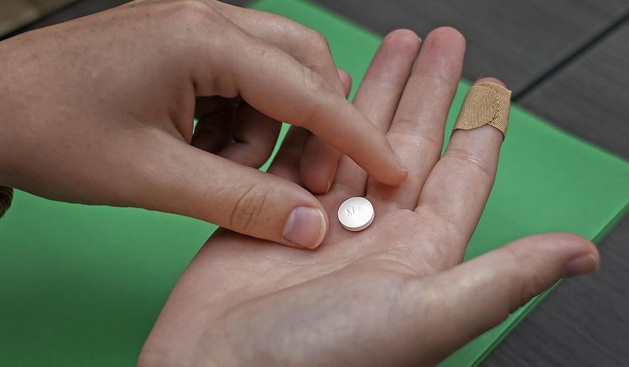 A patient prepares to take the first of two combination pills, mifepristone, for a medication abortion during a visit to a clinic in Kansas City, Kan., Oct. 12, 2022. (AP Photo/Charlie Riedel) **FILE**