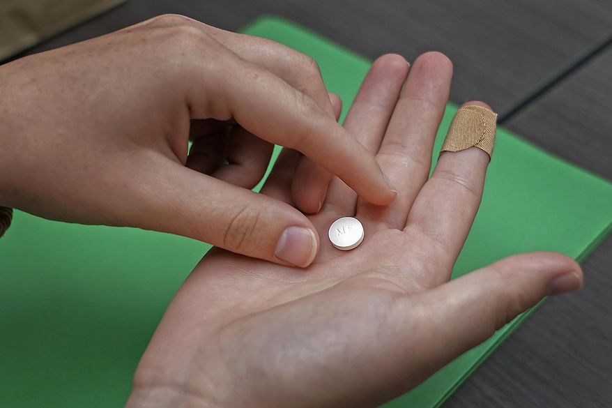 A patient prepares to take the first of two combination pills, mifepristone, for a medication abortion during a visit to a clinic in Kansas City, Kan., Oct. 12, 2022. (AP Photo/Charlie Riedel) **FILE**