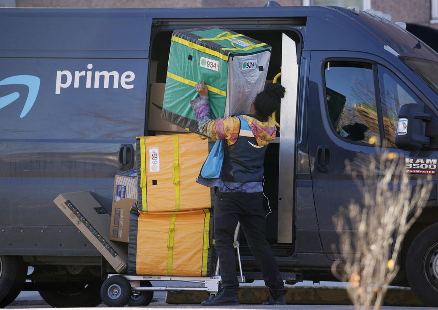 FILE - An Amazon Prime delivery person lifts packages while making a stop at a high-rise apartment building, Nov. 28, 2023, in Denver. (AP Photo/David Zalubowski, File)