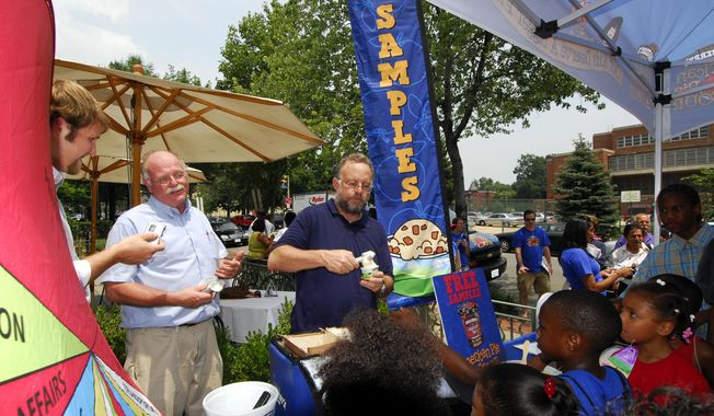 Ben Cohen, second from left, and Jerry Greenfield, center, founders of Ben & Jerry Homemade Inc., serve ice cream to Washington residents July 12, 2006, to kick off a federal budgets priority campaign. (AP Photo/Nick Wass) ** FILE **