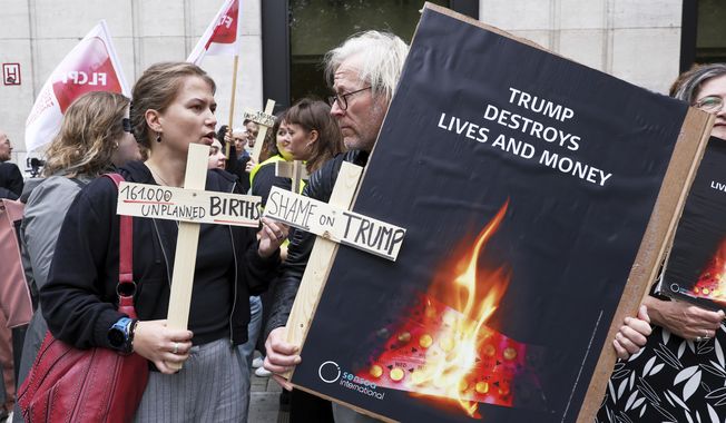 Participants from various women's rights organizations hold signs as they demonstrate regarding the destruction of family planning supplies stockpiled in Belgium, near the U.S. embassy in Brussels, Thursday, Sept. 18, 2025. (AP Photo/Omar Havana)