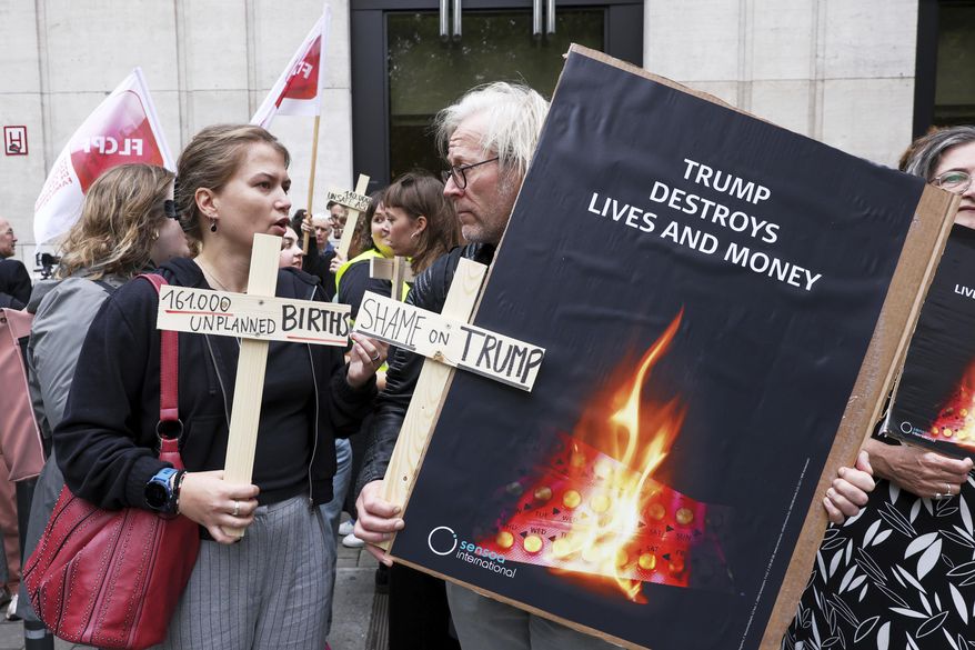 Participants from various women's rights organizations hold signs as they demonstrate regarding the destruction of family planning supplies stockpiled in Belgium, near the U.S. embassy in Brussels, Thursday, Sept. 18, 2025. (AP Photo/Omar Havana)
