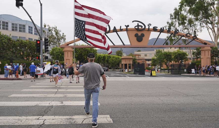 A U.S. flag is carried across a street in front of a demonstration in response to the suspension of Jimmy Kimmel's late-night show outside of Walt Disney Studios in Burbank, Calif., on Thursday, Sept. 18, 2025. (AP Photo/Jae C. Hong)