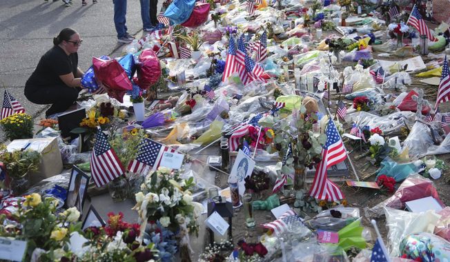 A well-wisher pauses at a growing makeshift memorial set up at the Turning Point USA headquarters after the shooting death at a Utah college last Wednesday of Charlie Kirk, the 31-year-old founder and CEO of the organization, Wednesday, Sept. 17, 2025, in Phoenix. (AP Photo/Ross D. Franklin)