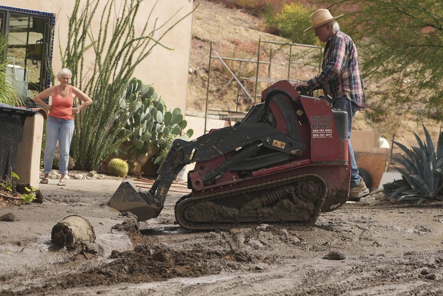 Residents clean up the damage caused by mudslides after storms in Yucaipa, Calif., Friday, Sept. 19, 2025. (AP Photo/Damian Dovarganes)