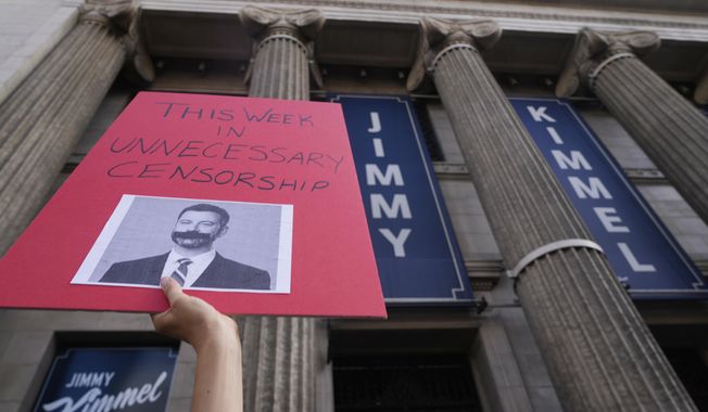 A demonstrator holds a sign outside El Capitan Entertainment Centre, where the late-night show "Jimmy Kimmel Live!" is staged on Thursday, Sept. 18, 2025, in Los Angeles. (AP Photo/Damian Dovarganes)