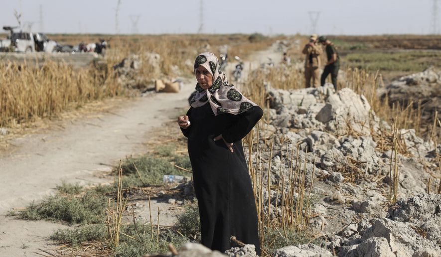 Samira Alloush, searching for her missing son, cries as she watches the Syrian Civil Defense workers inspect clothes found alongside human remains in Otaiba, on the outskirts of Damascus, Syria, Friday, Sept. 19, 2025. (AP Photo/Omar Albam)